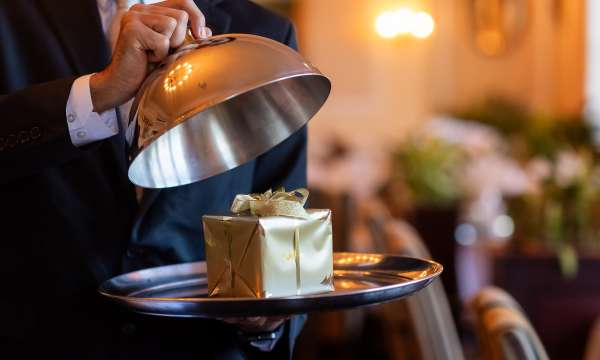 Staff member opening cloche to reveal Christmas present
