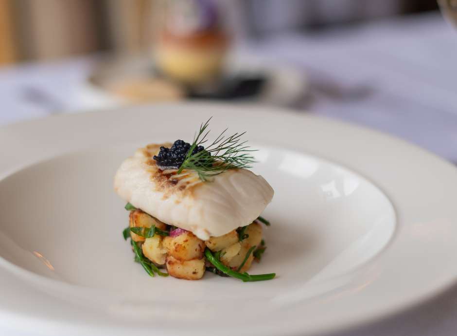 Fish on a bed of potatoes on a white plate