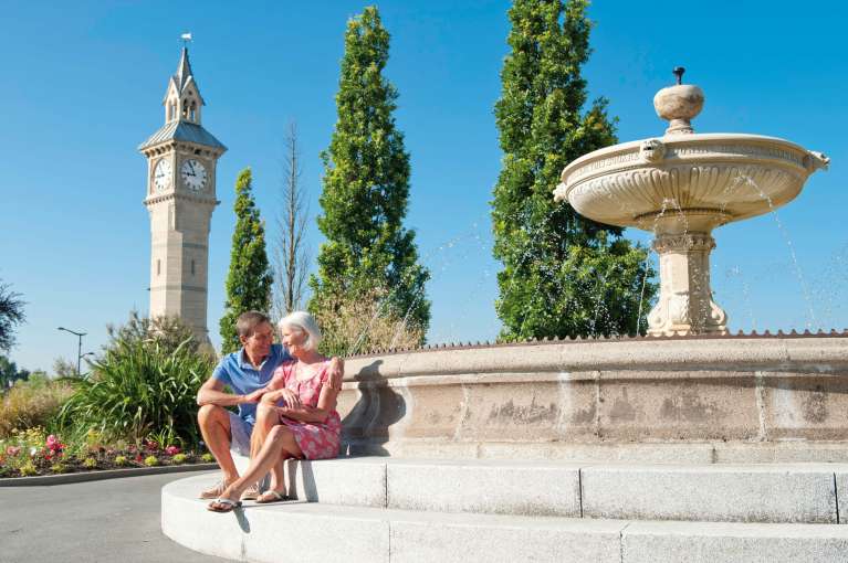 Imperial Hotel Couple Sitting by Fountain on Barnstaple Square with Clock Tower Behind Them