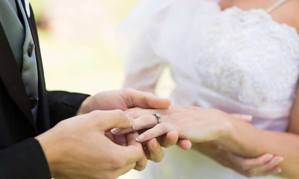 Groom putting wedding ring on the Brides finger