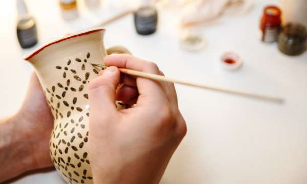 Person painting a pot 