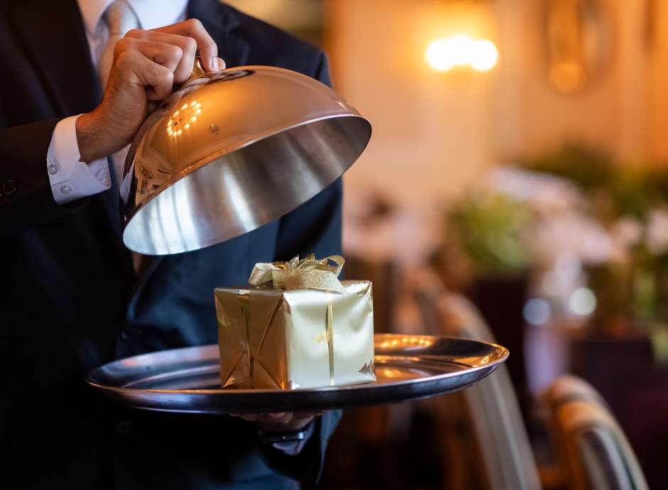 Staff member opening cloche to reveal Christmas present 