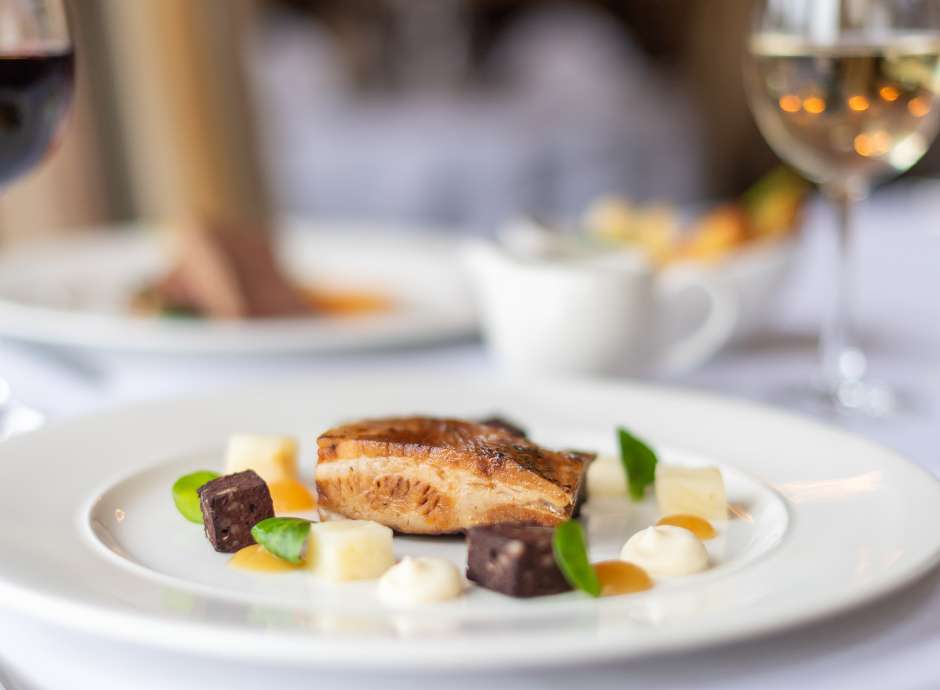 Pork dish on a table with white and red wine
